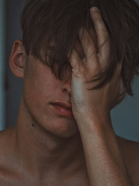 Person hält sich erschöpft das Gesicht, Ausdruck von Angst oder innerer Anspannung