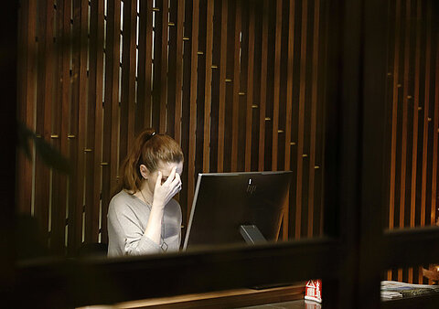 Mitarbeiterin im öffentlichen Dienst sitzt mit Burnout vor einem Computer