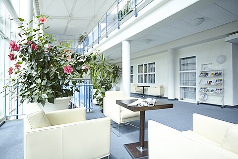 Lichtdurchfluteter Aufenthaltsbereich der Privatklinik mit Lounge-Möbeln