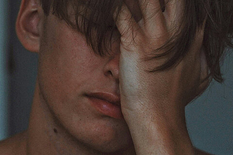 Person hält sich erschöpft das Gesicht, Ausdruck von Angst oder innerer Anspannung