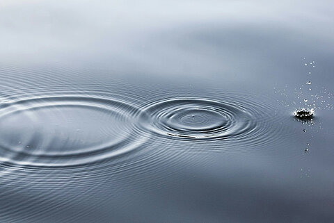 Wassertropfen auf einem stillen Gewässer